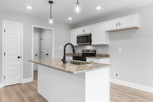 kitchen featuring sink, a kitchen island with sink, pendant lighting, and white cabinetry