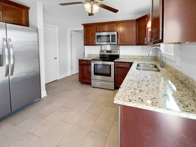 kitchen featuring ceiling fan, appliances with stainless steel finishes, light tile patterned flooring, light stone countertops, and sink