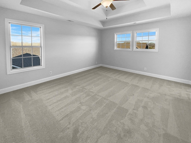 spare room featuring ceiling fan, carpet flooring, and a tray ceiling