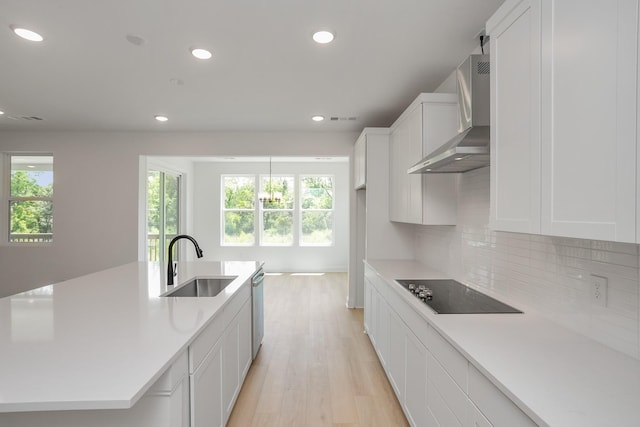 kitchen featuring black electric cooktop, sink, white cabinetry, wall chimney range hood, and backsplash