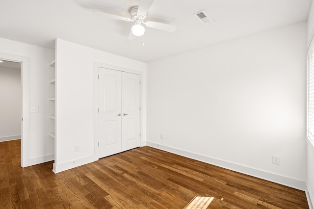 unfurnished bedroom featuring dark wood-type flooring, ceiling fan, and a closet