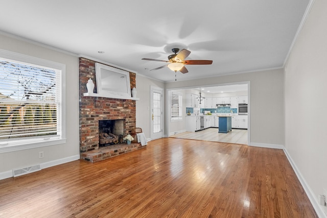 unfurnished living room featuring ceiling fan, light wood-type flooring, a wealth of natural light, and a fireplace