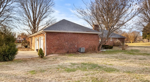 view of side of property with central air condition unit, a yard, and a garage