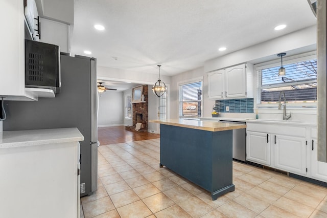 kitchen featuring white cabinets, pendant lighting, stainless steel dishwasher, and sink