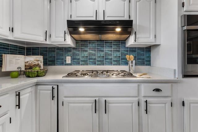 kitchen featuring white cabinets, light stone counters, appliances with stainless steel finishes, and decorative backsplash