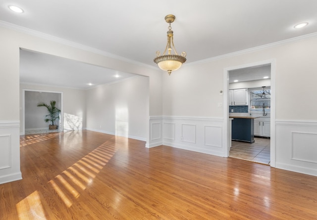 unfurnished room with ornamental molding and light wood-type flooring