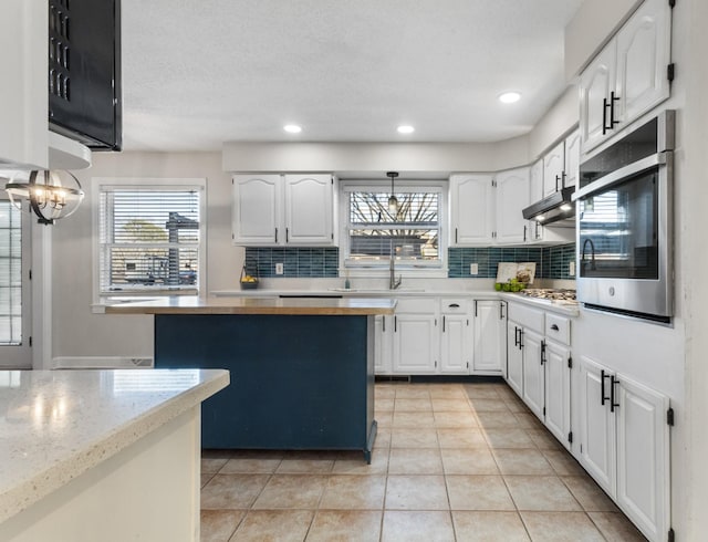 kitchen featuring sink, white cabinetry, backsplash, a kitchen island, and appliances with stainless steel finishes