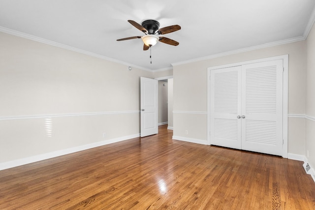 unfurnished bedroom featuring hardwood / wood-style floors, a closet, ceiling fan, and crown molding