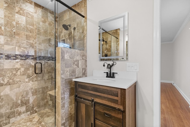 bathroom featuring hardwood / wood-style flooring, a shower with shower door, crown molding, and vanity