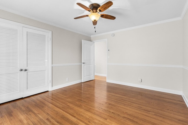 unfurnished bedroom featuring hardwood / wood-style flooring, ceiling fan, crown molding, and a closet