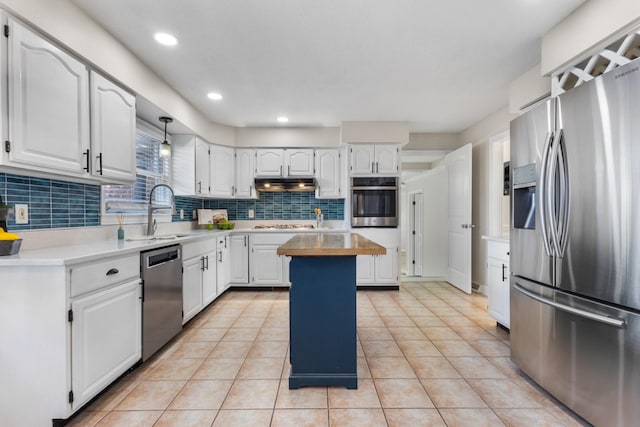 kitchen with appliances with stainless steel finishes, light tile patterned floors, decorative backsplash, a kitchen island, and white cabinets