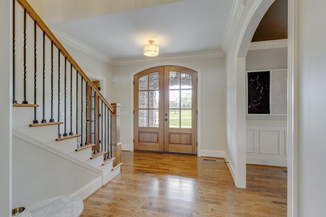 entrance foyer with french doors, crown molding, and light hardwood / wood-style floors