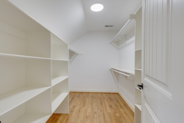 spacious closet with vaulted ceiling and light hardwood / wood-style flooring