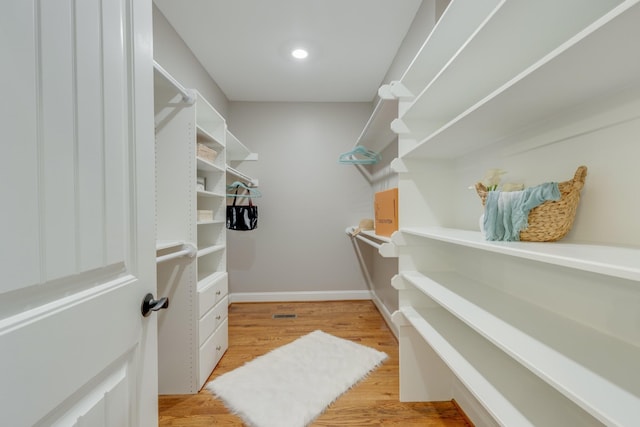 walk in closet with light hardwood / wood-style floors