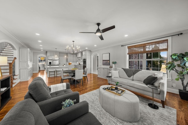 living room with ornamental molding, ceiling fan with notable chandelier, and hardwood / wood-style flooring