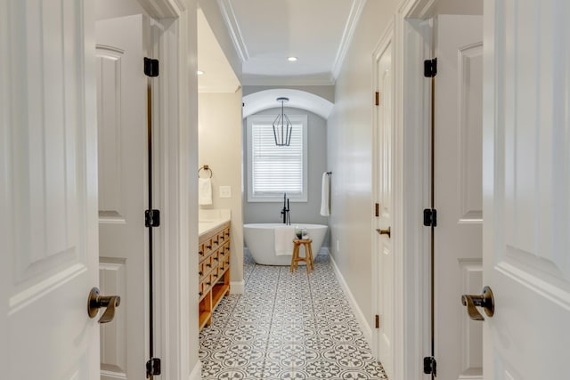 bathroom featuring a washtub, tile patterned flooring, ornamental molding, and vanity