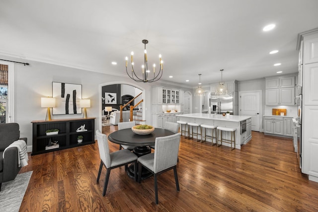 dining room with dark wood-type flooring, an inviting chandelier, and crown molding