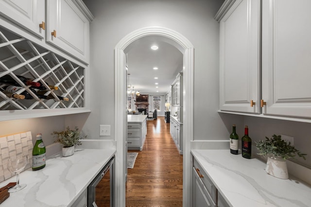 bar featuring white cabinets, beverage cooler, and light stone countertops