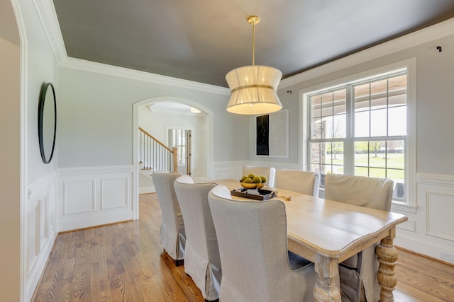 dining space featuring light wood-type flooring, crown molding, and plenty of natural light