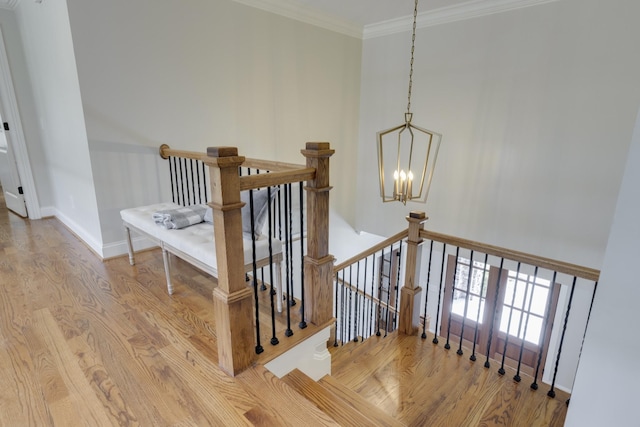 staircase with ornamental molding, an inviting chandelier, and wood-type flooring