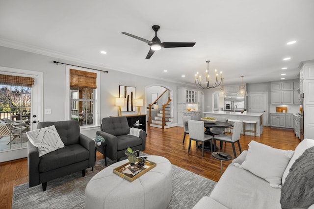 living room featuring sink, hardwood / wood-style floors, crown molding, and ceiling fan with notable chandelier