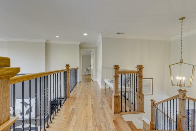 hallway with ornamental molding, a notable chandelier, and light hardwood / wood-style floors