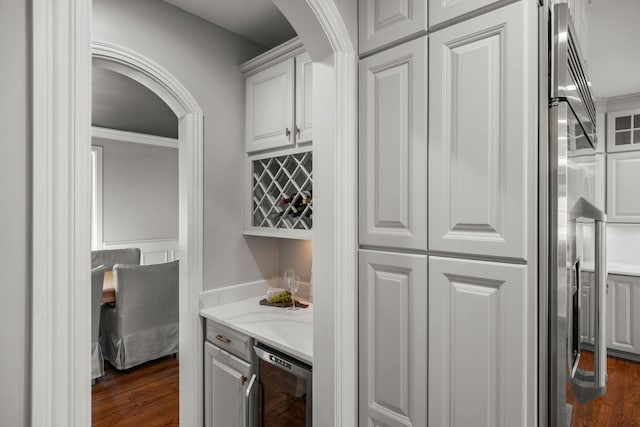 bar featuring decorative backsplash, white cabinetry, refrigerator with ice dispenser, and crown molding