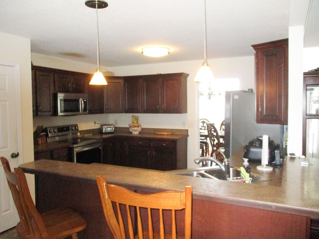 kitchen with stainless steel appliances, a kitchen breakfast bar, hanging light fixtures, sink, and kitchen peninsula