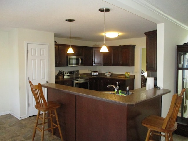 kitchen with a breakfast bar area, hanging light fixtures, kitchen peninsula, stainless steel appliances, and dark brown cabinets