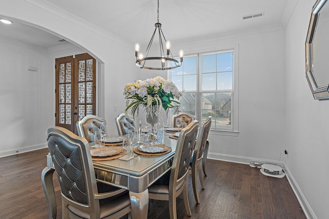 dining area with crown molding, dark hardwood / wood-style floors, an inviting chandelier, and french doors