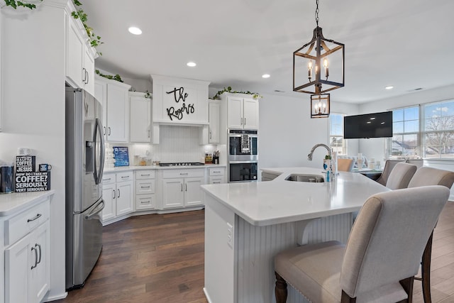 kitchen featuring stainless steel appliances, white cabinetry, sink, and pendant lighting