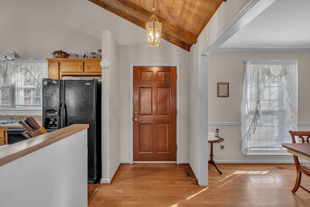 kitchen with lofted ceiling with beams, a healthy amount of sunlight, pendant lighting, and black fridge with ice dispenser