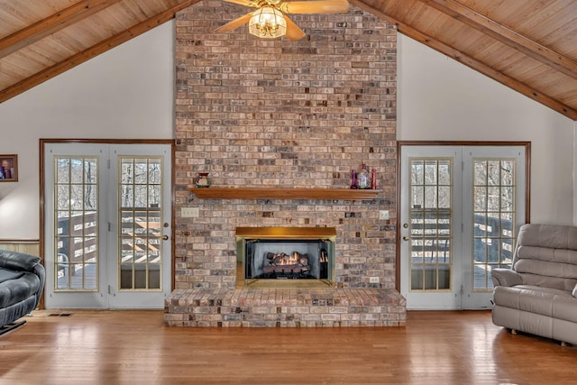 living room with wood-type flooring, beam ceiling, high vaulted ceiling, and a brick fireplace