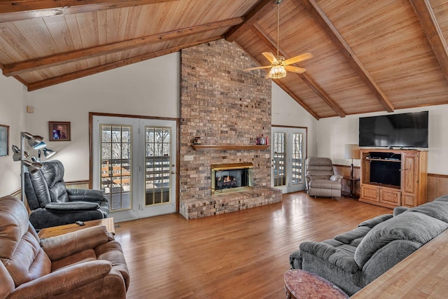 living room with beam ceiling, a brick fireplace, high vaulted ceiling, and wood ceiling