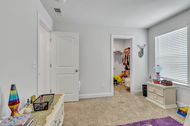 bedroom featuring light colored carpet, a spacious closet, and a closet