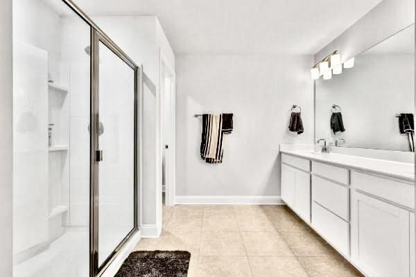 bathroom featuring tile patterned flooring, an enclosed shower, and vanity