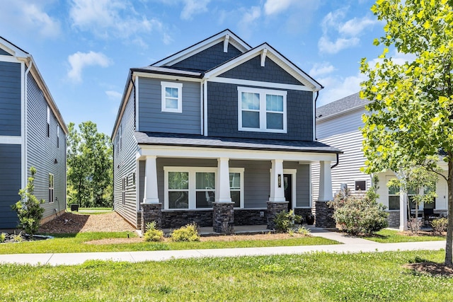 craftsman inspired home featuring covered porch and a front lawn