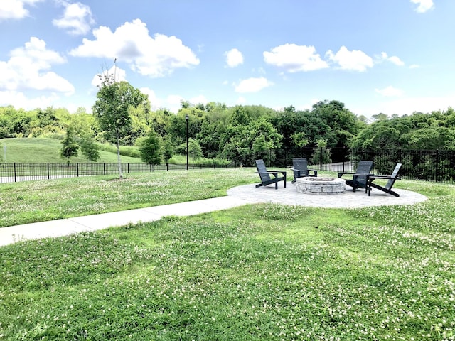 view of property's community featuring a patio, a lawn, and a fire pit