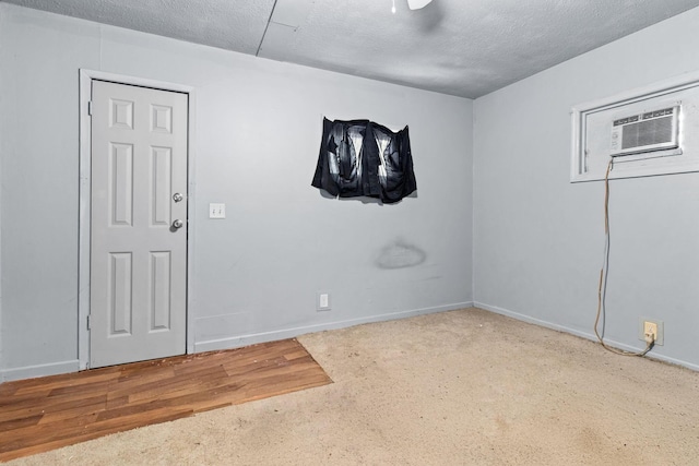 unfurnished room featuring a wall unit AC, carpet floors, and a textured ceiling