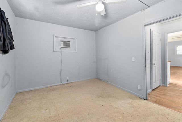 carpeted spare room with ceiling fan, a wall mounted AC, and a textured ceiling