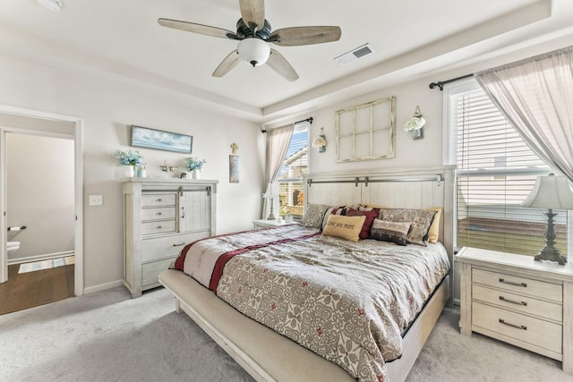 carpeted bedroom featuring ceiling fan and a tray ceiling