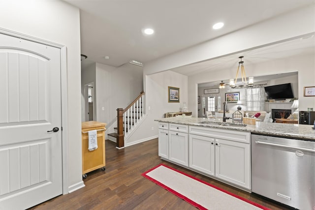 kitchen with light stone counters, dishwasher, hanging light fixtures, white cabinetry, and sink