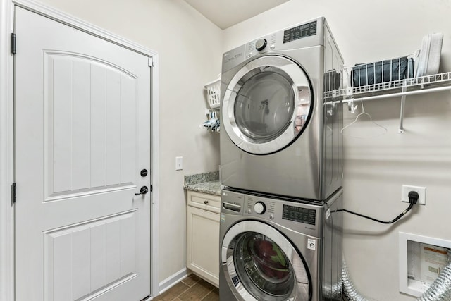 washroom with cabinets and stacked washer / drying machine