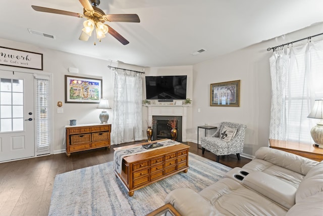 living room featuring ceiling fan, a wealth of natural light, and dark hardwood / wood-style floors