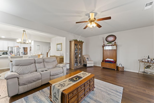 living room with ceiling fan with notable chandelier and dark wood-type flooring