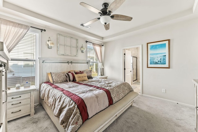 carpeted bedroom with multiple windows, ceiling fan, ensuite bath, and a raised ceiling