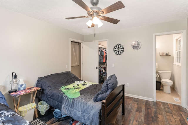 bedroom with a spacious closet, ensuite bathroom, ceiling fan, a closet, and dark hardwood / wood-style flooring