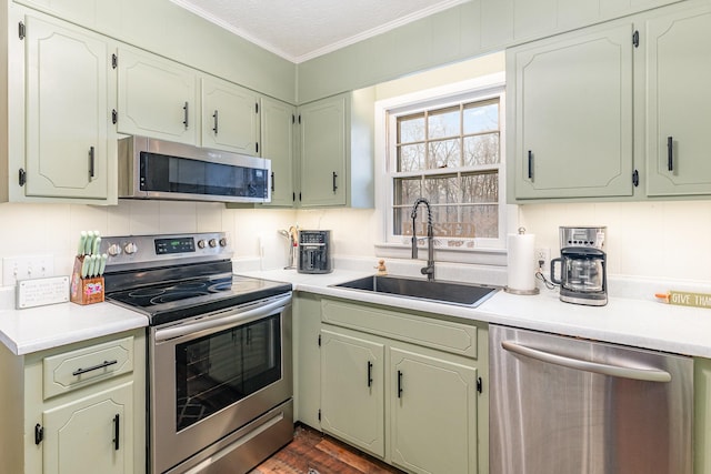 kitchen featuring decorative backsplash, sink, a textured ceiling, stainless steel appliances, and ornamental molding