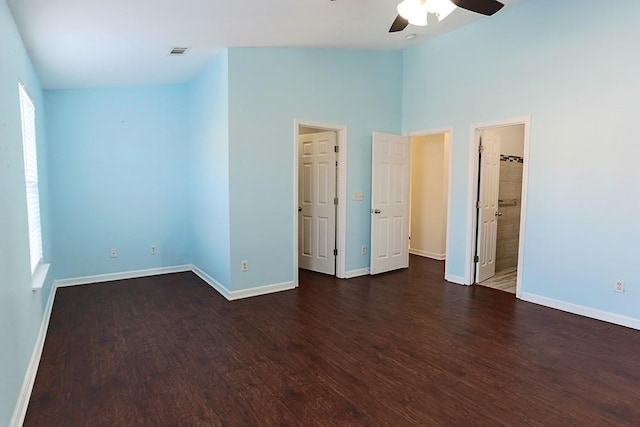 unfurnished bedroom with a towering ceiling, ensuite bath, ceiling fan, and dark hardwood / wood-style flooring