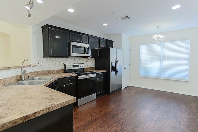 kitchen with an inviting chandelier, stainless steel appliances, dark hardwood / wood-style flooring, sink, and decorative light fixtures